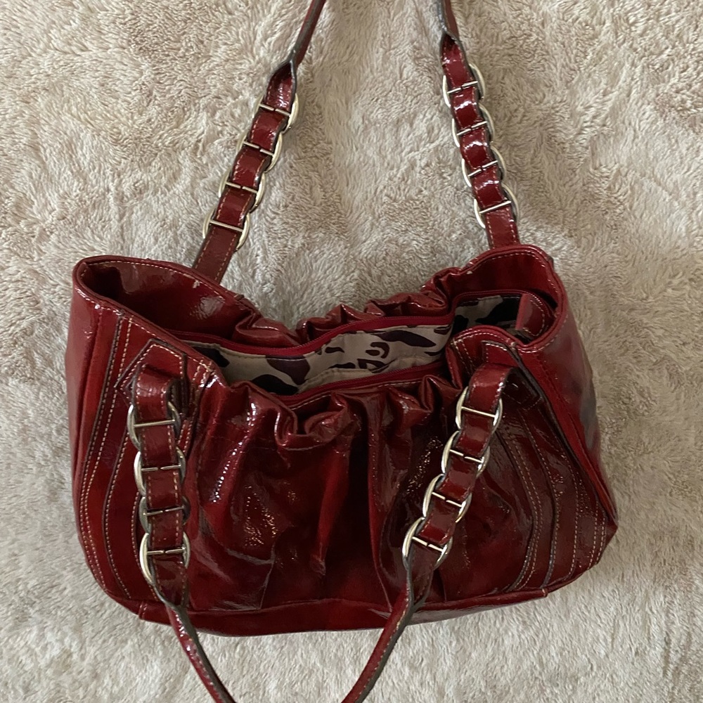 Red handbag with a black stain which is shown in the video.